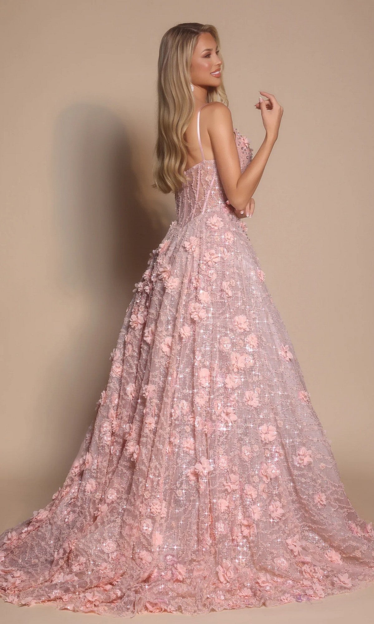 A woman with long blonde hair models the Portia and Scarlett PS26027 long formal dress, a floor-length pink A-line gown with thin straps and delicate floral embellishments, posing against a beige background.
